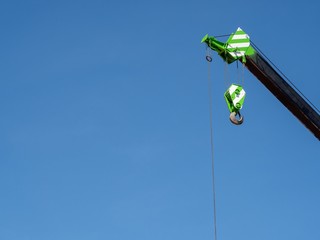 Black green telescopic arm of a mobile crane against deep blue sky in construction site.