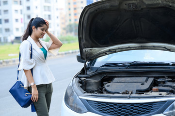Young Indian woman waiting for mechanic for help after her car breakdown on road , young girl and her broken car with open hood.