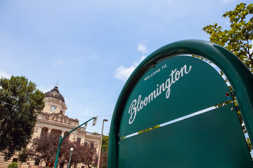 Welcome to Bloomington Indiana sign with downtown courthouse in the background