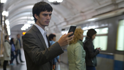 Fototapeta na wymiar Handsome businessman using smartphone in a subway