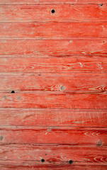 Old wooden boards on a fence painted with red paint