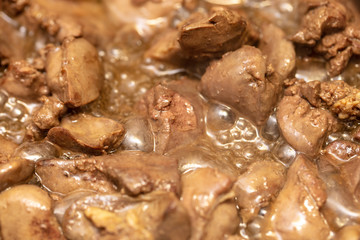 Chicken liver is fried in a pan.