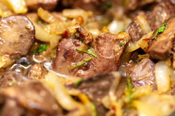 Chicken liver is fried in a pan.