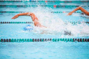 Motion blurred swimmers in a freestyle race, focus on water drops