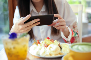 Asia beautiful woman taking photo on her waffles in the coffee shop and prepared to upload to a...