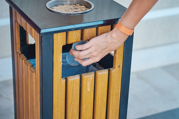 Woman hand throwing plactic cup for water in a trash bin