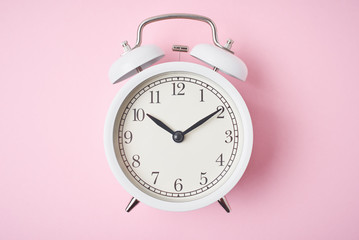 White retro alarm clock on the pink background with copy space. Time concept