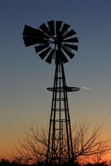 Kansas colorful Sunset with tree's,clouds, and a Windmill silhouette north of Hutchinson Kansas USA out in the country.