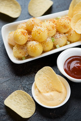 Close-up of potato balls topped with parmesan cheese and potato chips, vertical shot, selective focus