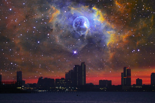 Nebula in galaxy over silhouette building on and city night sky