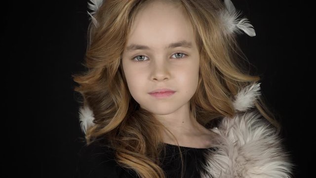 Serious beautiful fashionable little girl looking at camera. Portrait of alone stylish gorgeous kid model in glamour pose in studio. Face expression of attractive blonde child preschool closeup indoor