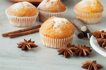 Tasty muffins with icing sugar on a wooden kitchen table ready to eat. Cinnamon sticks and star anise. Sweet dessert.