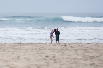 Fototapeta na wymiar A girl is playing in the sand at a California beach.