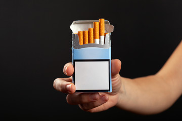 blue pack of cigarettes in hand on a dark background, mockup