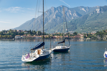 Boats moored on lake. Como lake, Italy. Panorama from the lakeside of the city of Lecco towards the village of Malgrate. Large and famous European lake located in northern Italy