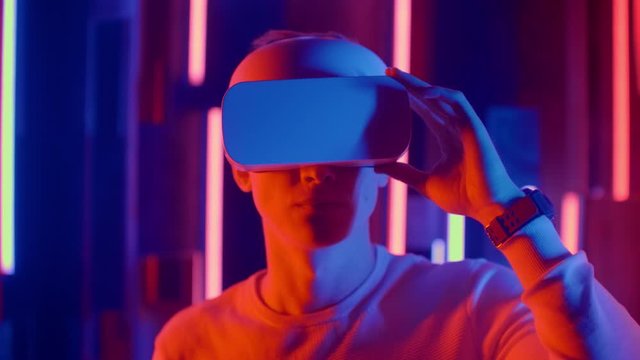 Futuristic virtual reality, a man in a helmet and neon light moves his hands while in virtual reality