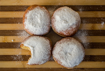 Homemade donuts, sprinkled with powdered sugar, one bitten