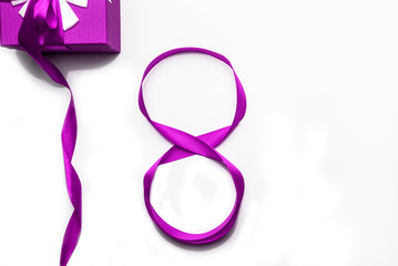 March 8 Womens Day concept. Number 8 from purple ribbon and purple gift box on white background,isolated.Flat lay