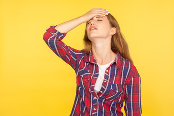 Facepalm. Portrait of regretful unhappy ginger girl in casual shirt holding hand on face, feeling desperate about loss, sorrow for mistake, bad memory. indoor studio shot isolated on yellow background