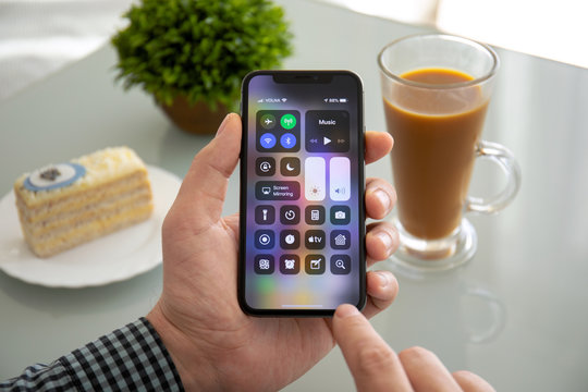 Man hand holding iPhone X with home screen Control Center