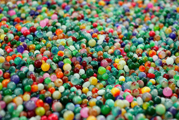 Colourful stone beads scattered throughout the background. Pattern, Texture, Decoration, Wallpaper.
