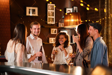 Happy group of friends at the bar having drinks. - obrazy, fototapety, plakaty