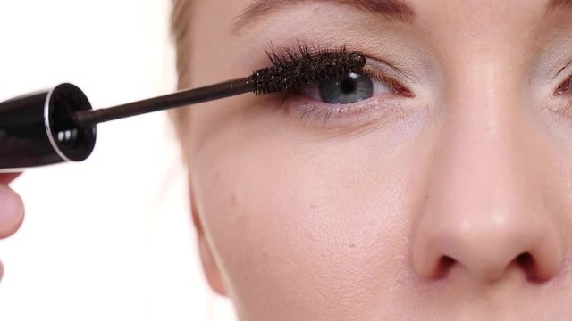 Cosmetic beauty procedures and makeover concept. Closeup woman face eyes painting. Makeup artist applying brown mascara to model eye. Slow motion