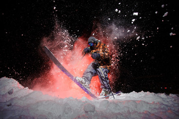 Active male snowboarder dressed in a grey orange sportswear jumping under the snow with sticks