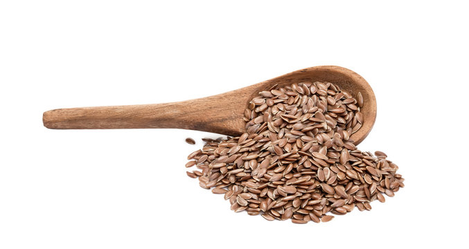 Side view of linseeds or flax seed on a tilted brown wooden spoon with spill and handle to the left isolated on white background