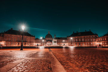 Night long exposure panoramic view after rain of Amalienborg winter residence 18th-century rococo complex of palaces with museum & marches/displays by royal guards in Copenhagen, Denmark. 