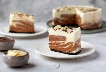 Two pieces of homemade raw chocolate cheesecake or mousse cake, decorate with almond flakes and chocolate morsels