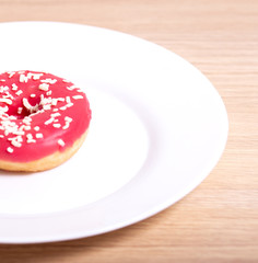 doughnut lies on a white plate on a cork background