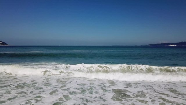 砂浜に打ち寄せて広がる波 真っ白な波頭 青い海と空の背景 フィックス 
