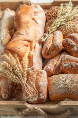 Tasty baguettes and buns on wooden table