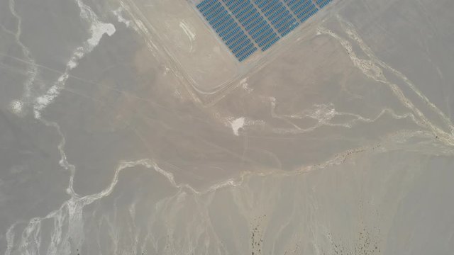Aerial overhead to high angle view footage hundreds solar energy modules or panels rows along the dry arid lands at Atacama Desert, Chile. A photovoltaic solar energy modules symmetrical pattern