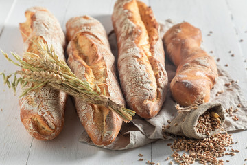 Homemade golden baguettes with grains and ears of wheat - obrazy, fototapety, plakaty