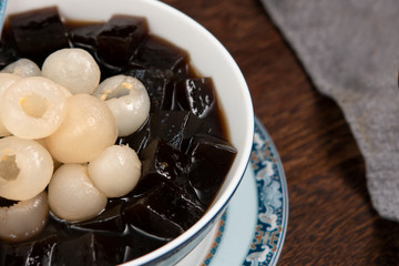 Black Grass Jelly Mesona chinensis, vegetable jelly, black in color, eaten with sugar. Pieces of grass jelly cut in bowl with colorful fruits on top (known as chaokuai, suong sao )