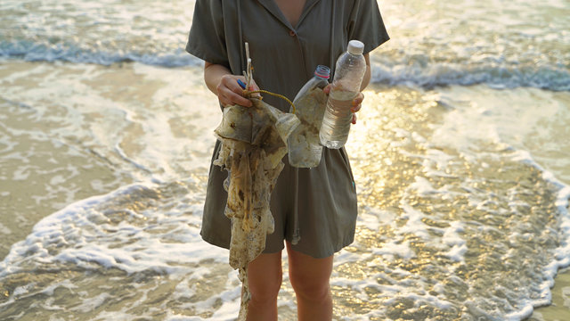 Young lady collected sea plastic garbage from the sea on a beach. Save the earth concept.