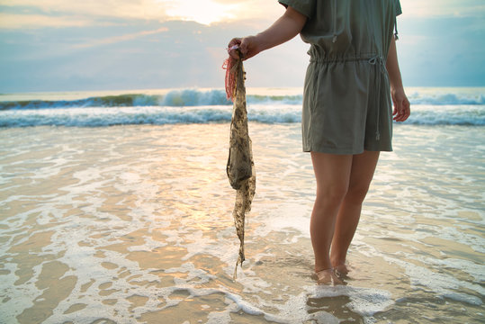 Young lady collected sea plastic garbage from the sea on a beach. Save the earth concept.