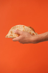 Mexican national food taco or Tatar national food kystyby in hand on an orange background.Food in a tortilla.National food concept