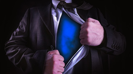 Superhero, young businessman tearing his shirt off isolated on dark background with copy space