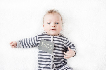 portrait of a cute baby in a striped suit with a sign on his chest