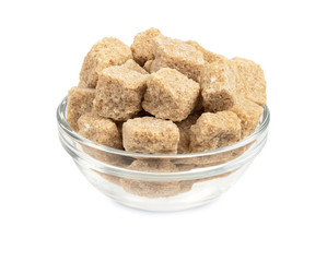 Rushy raw sugar cubes in the glass bowl isolated