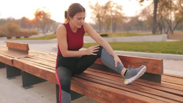 Young sportswoman having pain / injury during exercise and jogging in the park.