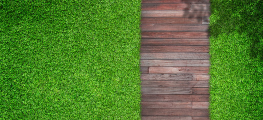 Outdoor gardening design of Top view green artificial grass with wooden footpath in garden.