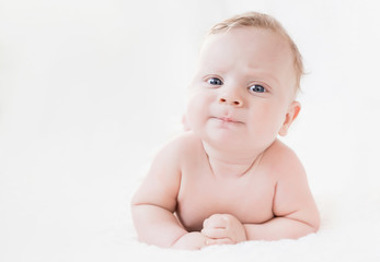 four month old white boy with blue eyes lying on his stomach on a white background