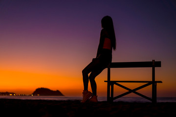 Fototapeta na wymiar Lifestyle, silhouette of a brunette sitting on a chair on the beach at night