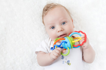 four-month-old boy chewing a rattle a white background
