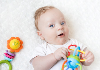 four-month-old boy chewing a rattle a white background