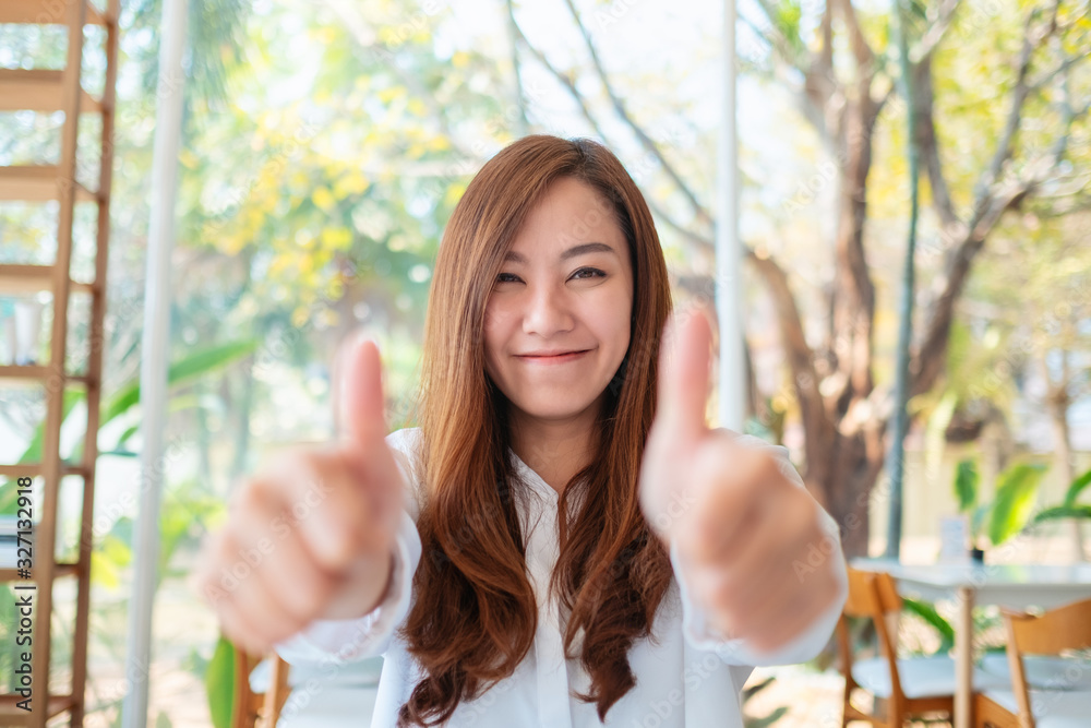 Wall mural a happy beautiful asian woman making and showing thumbs up hand sign